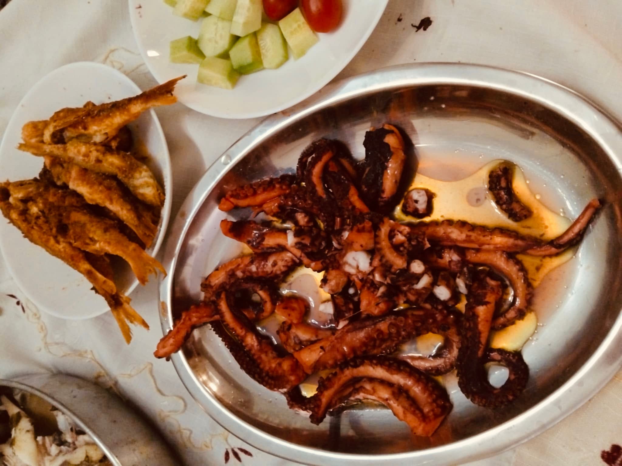 Grilled octopus, fried fish, and fresh sides — a feast on board